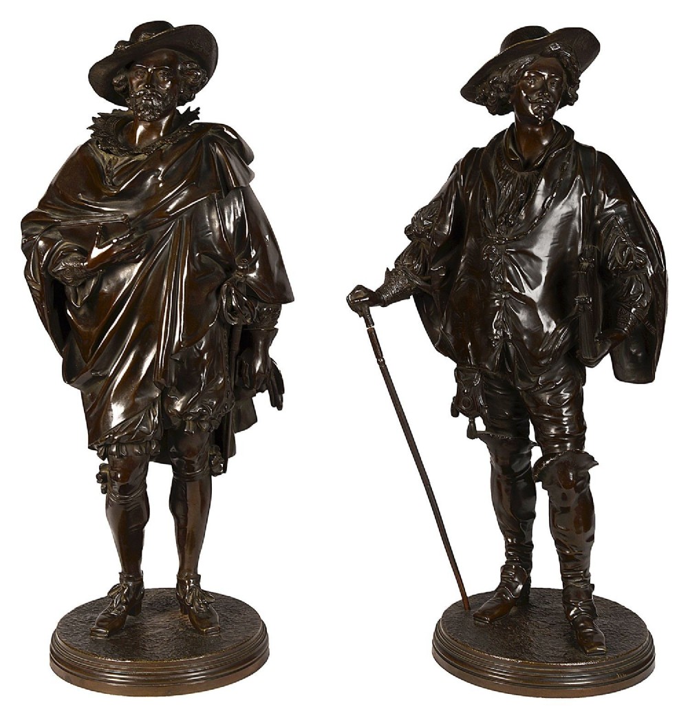 A pair of patinated dark bronze nineteenth-century sculptures depicting standing cavaliers in historical costume on round bases.