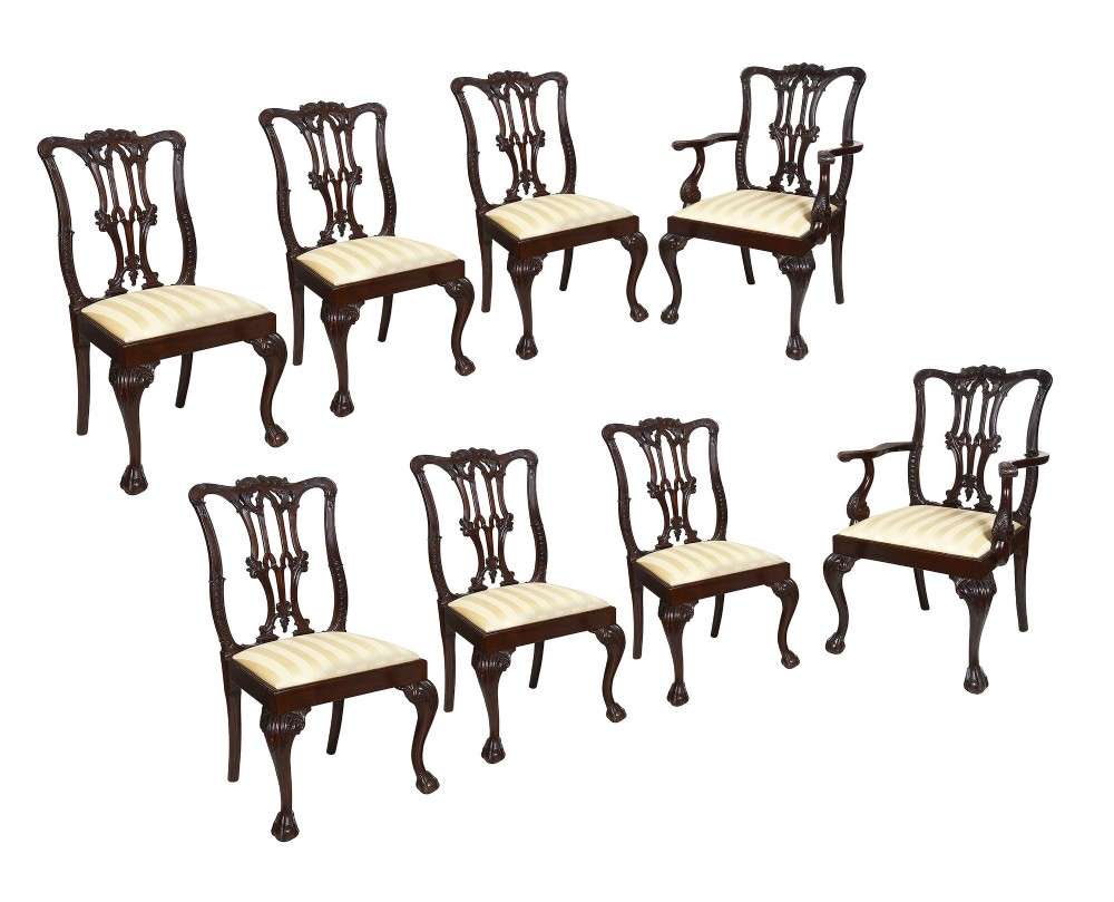 A set of eight 19th-century Chippendale style mahogany dining chairs featuring carved pierced splats, cabriole legs with ball-and-claw feet, and cream striped fabric seats.