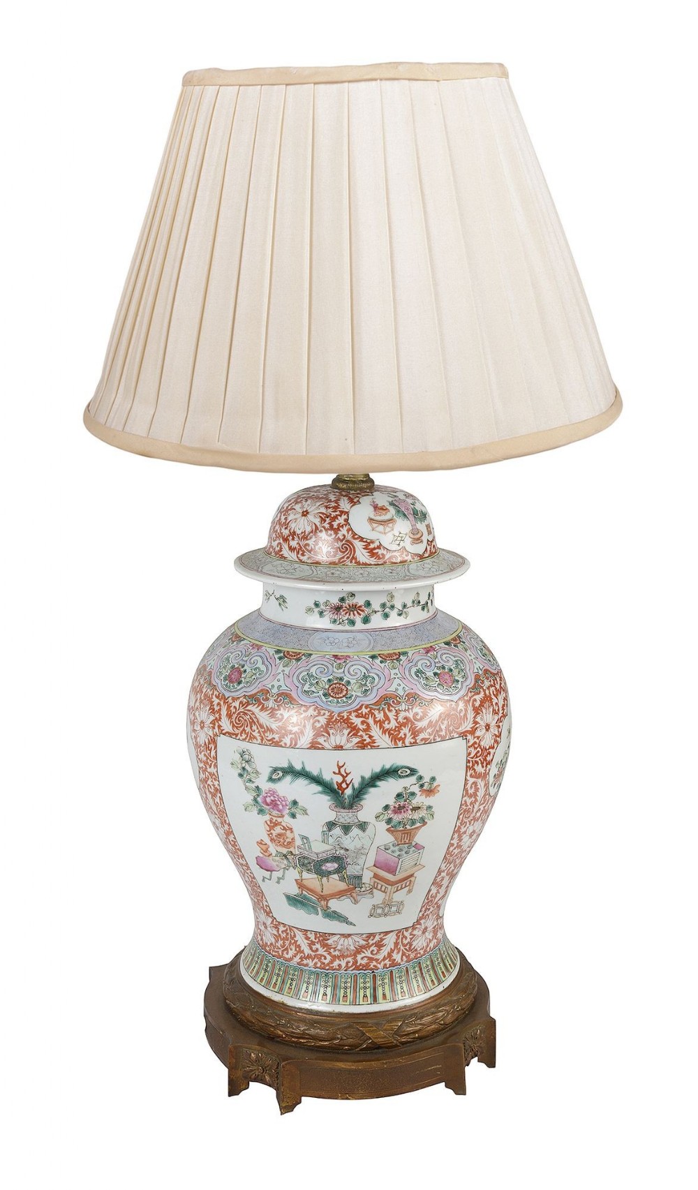 A 19th-century Chinese Famille Rose porcelain vase converted into a table lamp featuring polychrome painted panels, an iron-red scrolling ground, a metal base, and a pleated cream fabric shade.