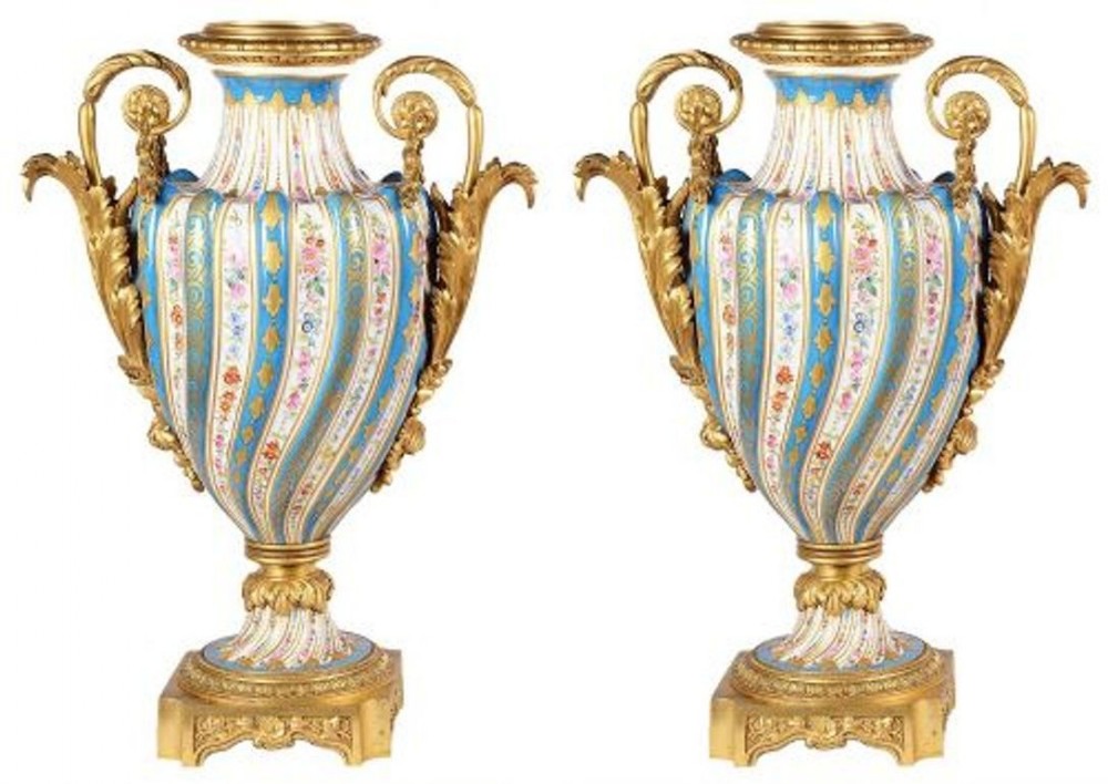 A pair of swirled blue and white porcelain vases featuring hand-painted floral sprigs and ornate gilt bronze handles on square bases.