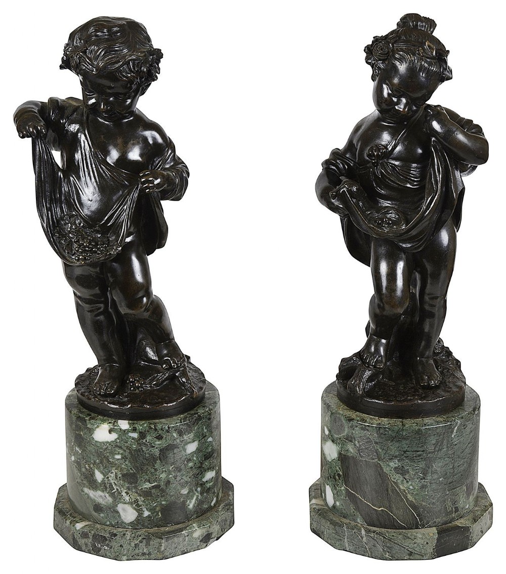 A pair of 19th-century dark patinated bronze statues depicting youthful cherubs gathering grapes, mounted on green marble bases.