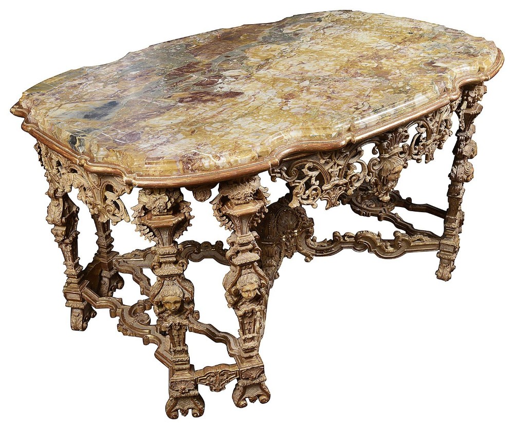 An 18th-century Italian style centre table with a variegated marble top and a heavily carved giltwood apron featuring cherub mascarons.