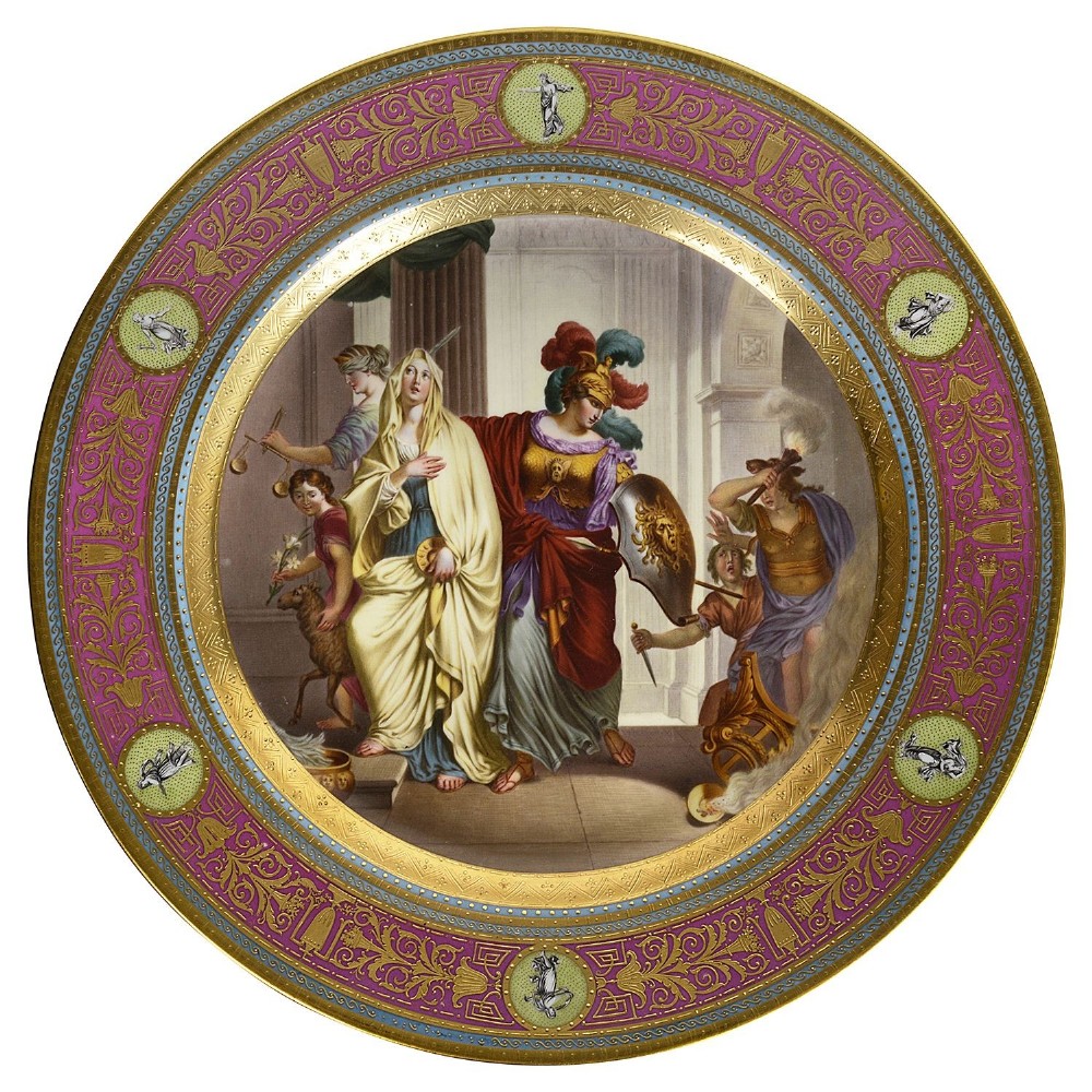 A circular porcelain charger featuring a hand-painted central classical figure scene surrounded by a wide magenta and raised gold ornamental border with green medallion accents.