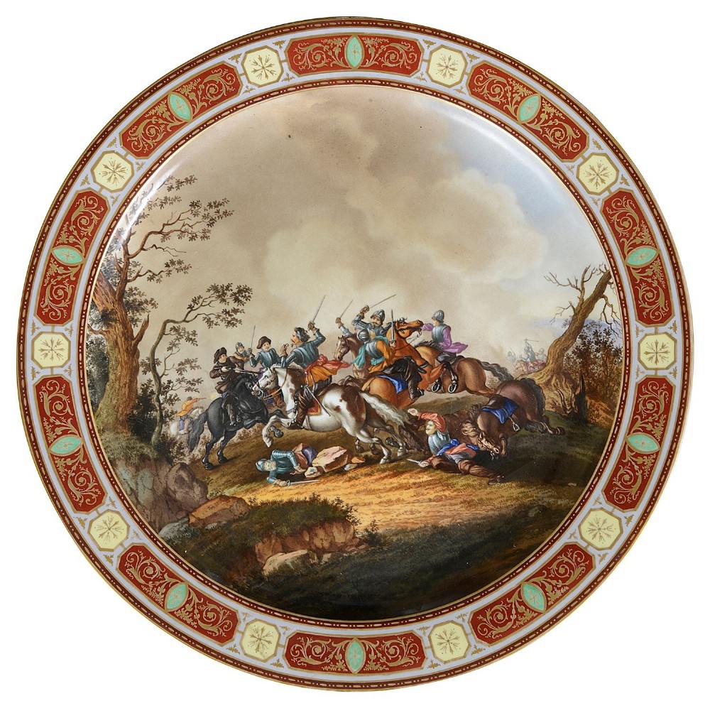 A circular 19th-century Vienna porcelain charger featuring a hand-painted central scene of cavalry soldiers on horseback surrounded by an ornate red and gold geometric border.