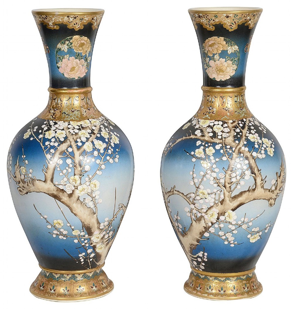 A pair of tall Japanese Satsuma baluster vases featuring gradient blue grounds decorated with hand-painted blossom trees and gilt geometric borders.