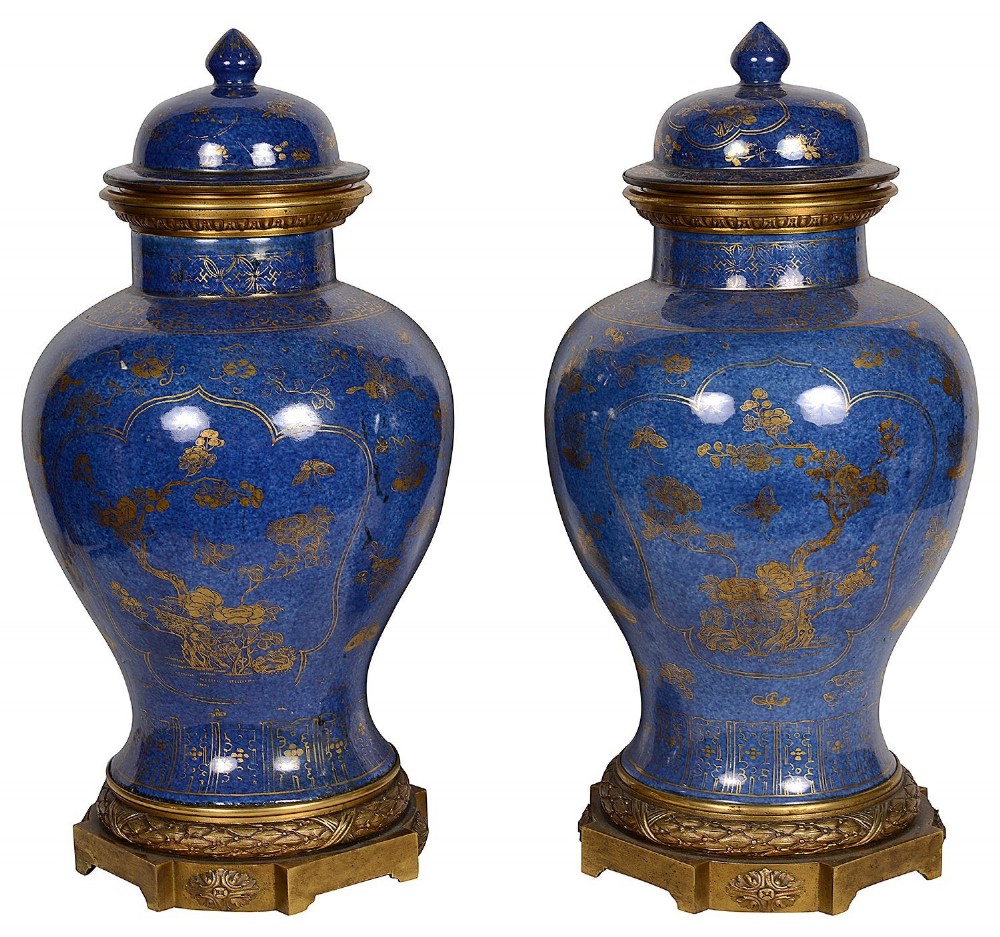 A pair of 19th-century powder blue porcelain baluster vases with gilt floral panels, domed covers, and decorative ormolu bases.