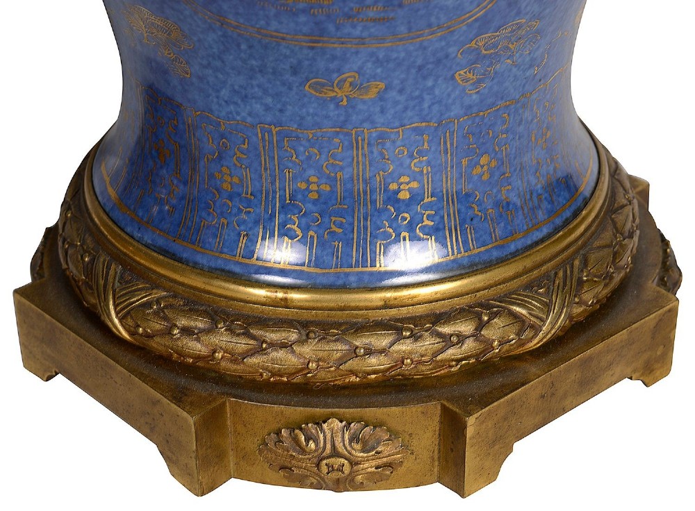 A pair of 19th-century powder blue porcelain baluster vases with gilt floral panels, domed covers, and decorative ormolu bases. View II