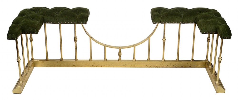 A Victorian brass club fender featuring vertical cylindrical spindles, a dipped front rail, and deep-buttoned green velvet corner seats with metal stud detailing. View V