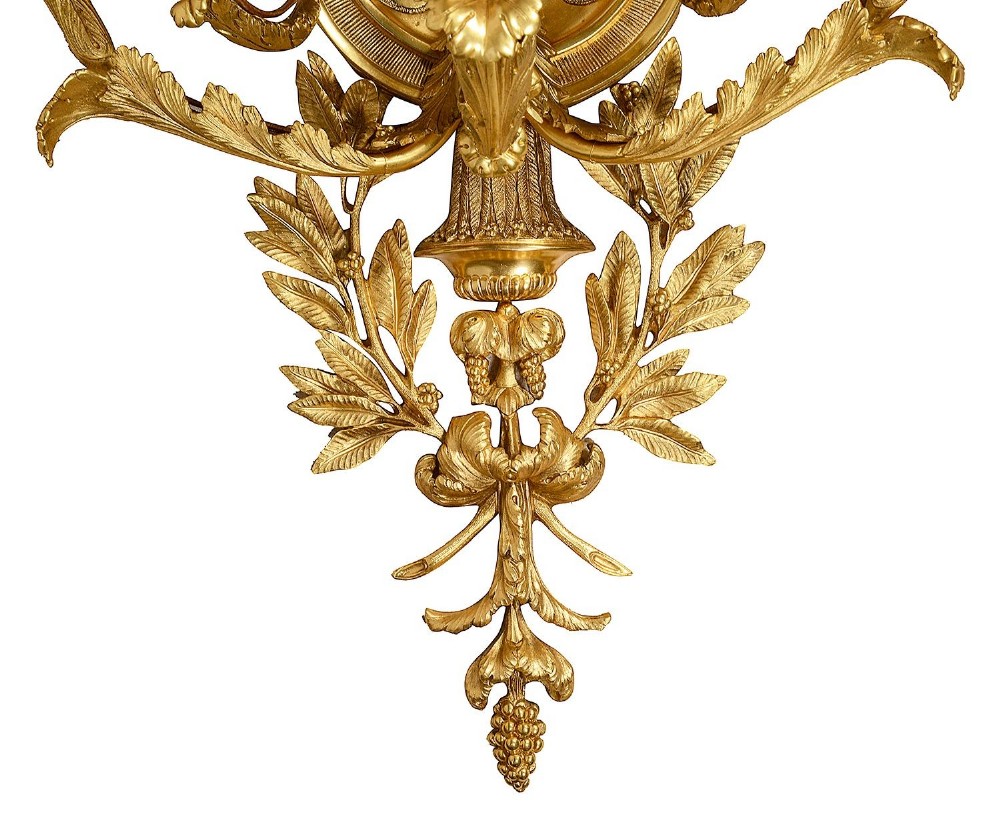 A set of six Louis XVI style gilded ormolu wall sconces featuring ribbon-bow finials and multi-arm candle holders adorned with leaf motifs. View V