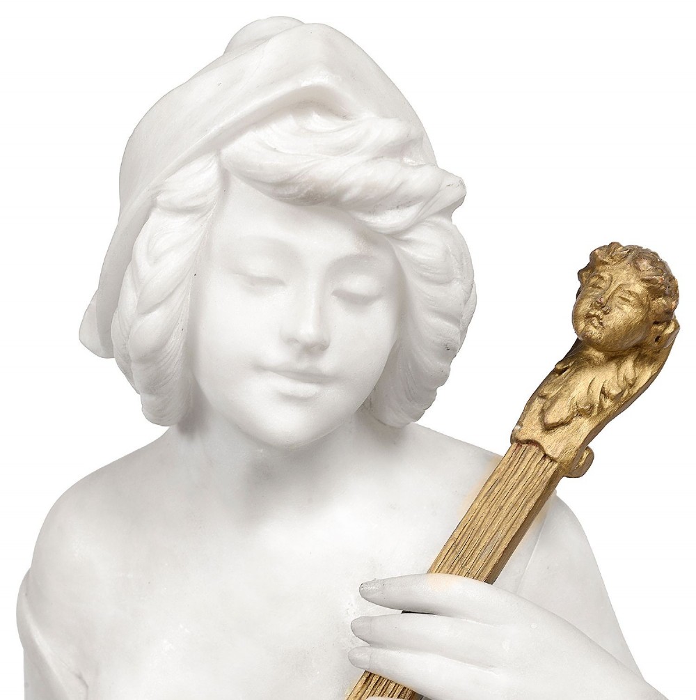 A carved white marble statue of a seated draped female musician playing a gilded lute on an integrated marble base. View II