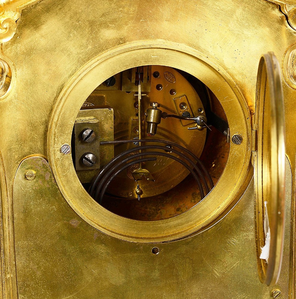 A 19th-century French Louis XVI style gilt bronze mantel clock decorated with multi-coloured enamel scrollwork and topped with twin cherub figures. View X