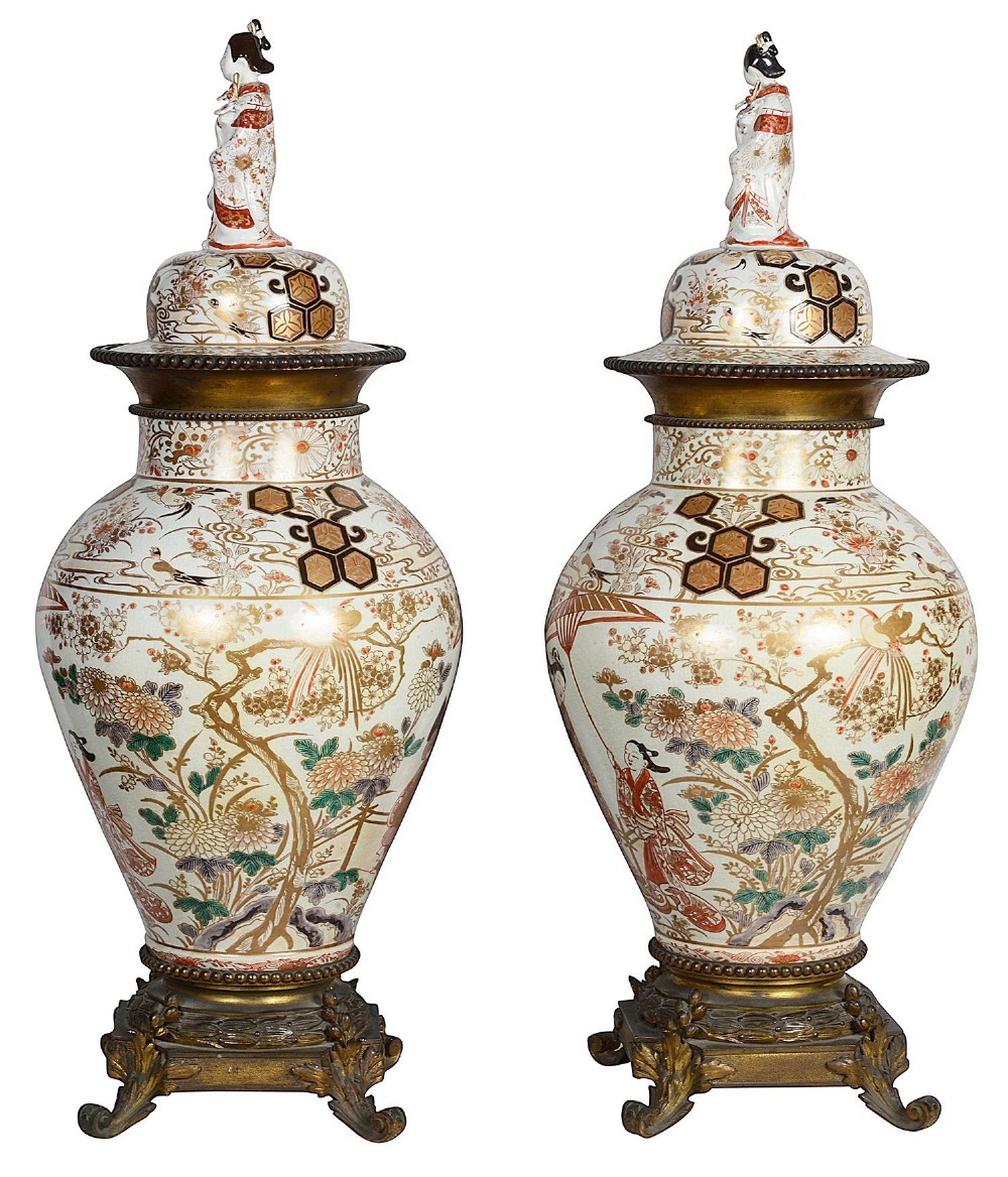 Pair of Japanese Arita Imari porcelain lidded vases featuring painted figures under umbrellas, standing on bronze bases with standing figure finials. View II
