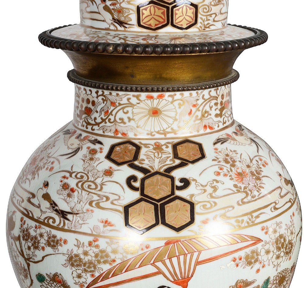 Pair of Japanese Arita Imari porcelain lidded vases featuring painted figures under umbrellas, standing on bronze bases with standing figure finials. View IV