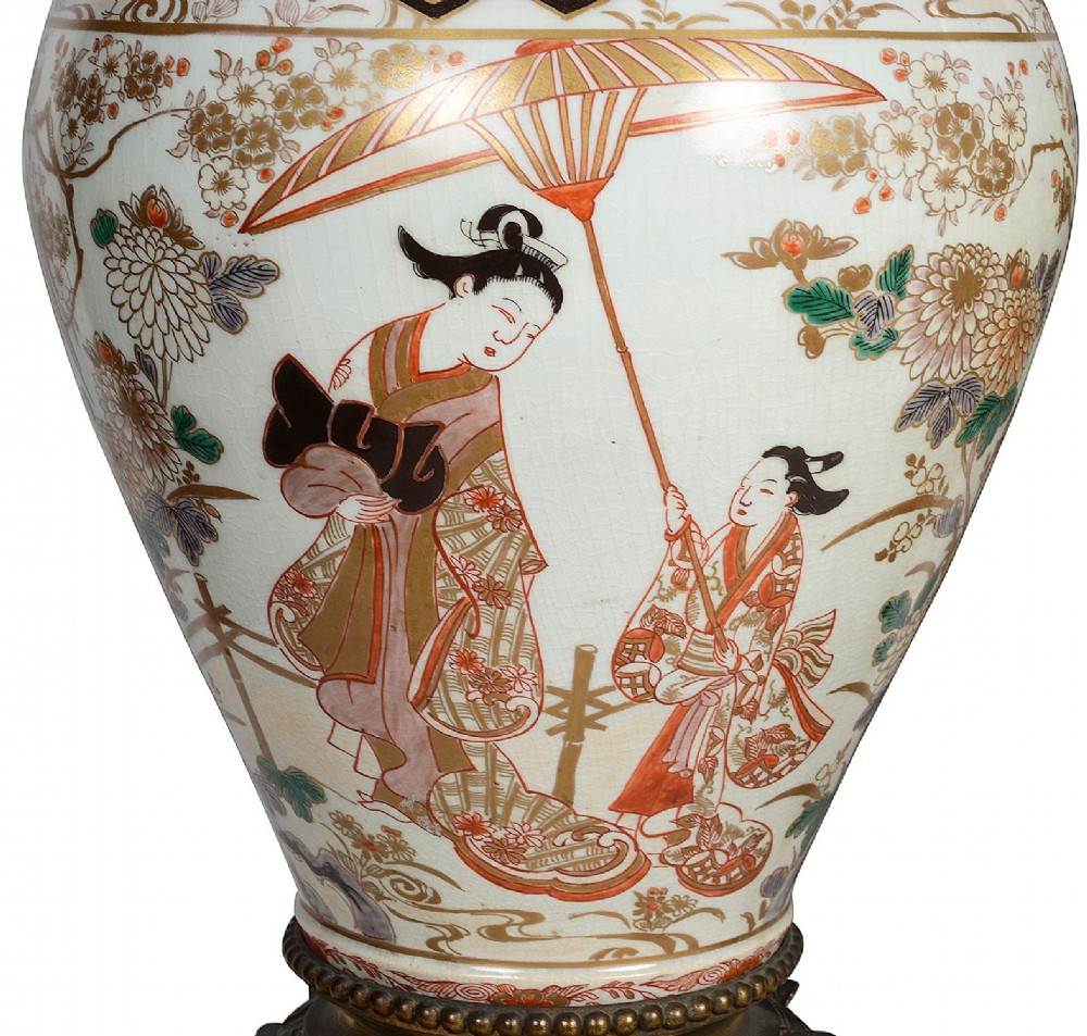 Pair of Japanese Arita Imari porcelain lidded vases featuring painted figures under umbrellas, standing on bronze bases with standing figure finials. View V
