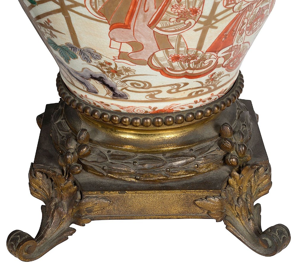 Pair of Japanese Arita Imari porcelain lidded vases featuring painted figures under umbrellas, standing on bronze bases with standing figure finials. View IX