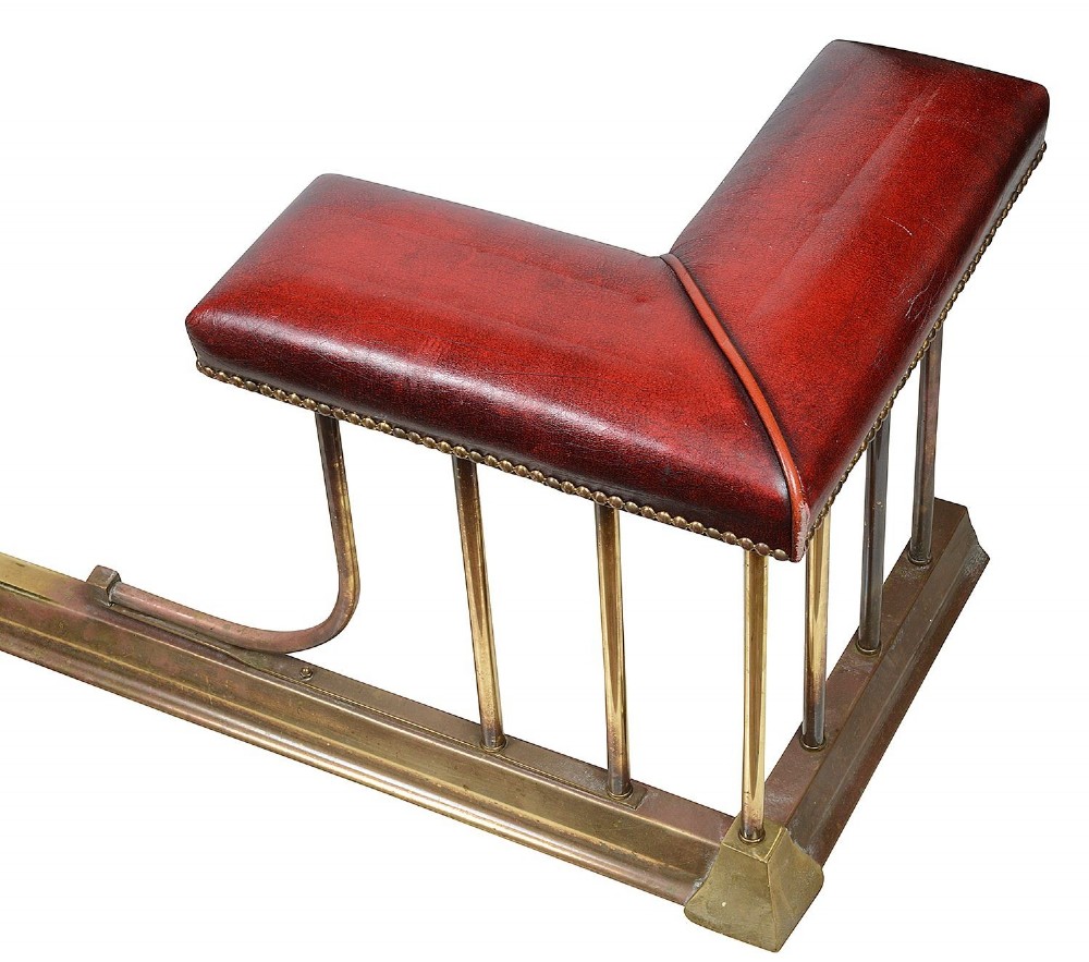 Late 19th-century brass club fender featuring twin red leather corner seats with stud trim and vertical brass spindles. View IV