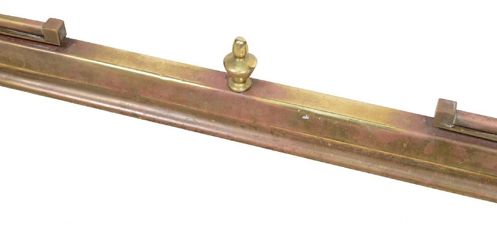 Late 19th-century brass club fender featuring twin red leather corner seats with stud trim and vertical brass spindles. View V