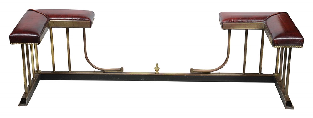 Late 19th-century brass club fender featuring twin red leather corner seats with stud trim and vertical brass spindles. View VI