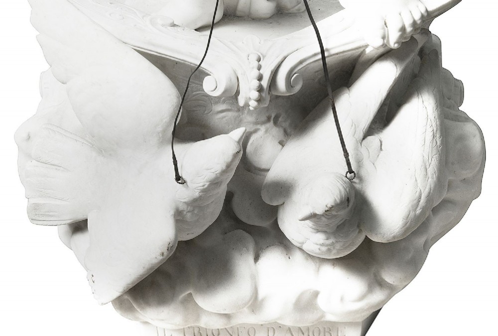 A 19th-century white carved marble sculpture depicting a child figure standing on a shell-shaped chariot pulled by a bird over clouds. View VII