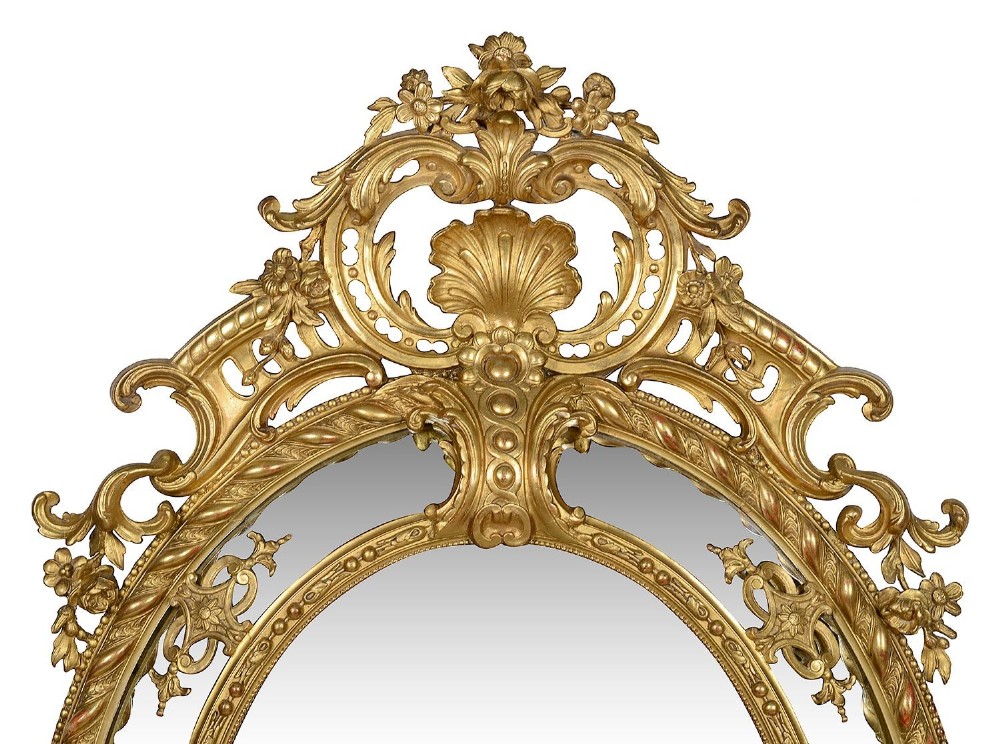 An ornate 19th-century oval wall mirror featuring a gilded wood and gesso frame with pierced scrollwork, shell cresting, and floral motifs. View III