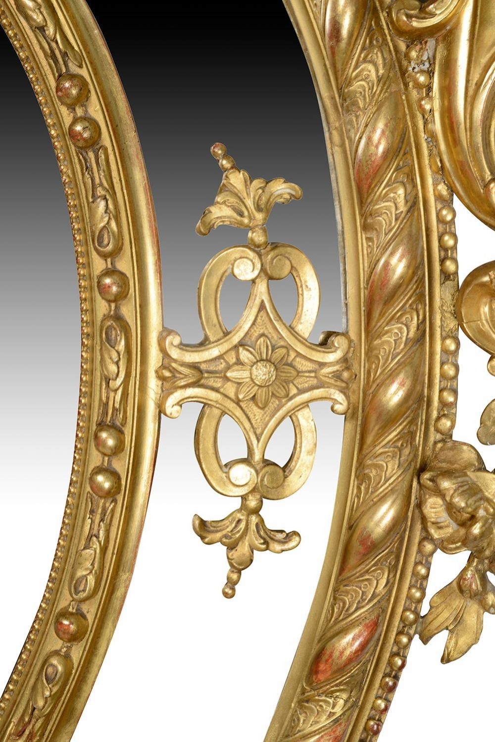 An ornate 19th-century oval wall mirror featuring a gilded wood and gesso frame with pierced scrollwork, shell cresting, and floral motifs. View VIII