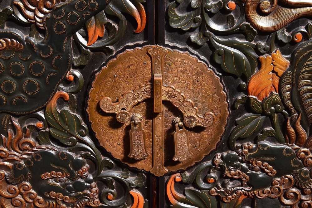 A late nineteenth-century black and polychrome carved lacquer cabinet featuring relief peony and dragon motifs, fitted brass hardware, and a matching stand base. View V