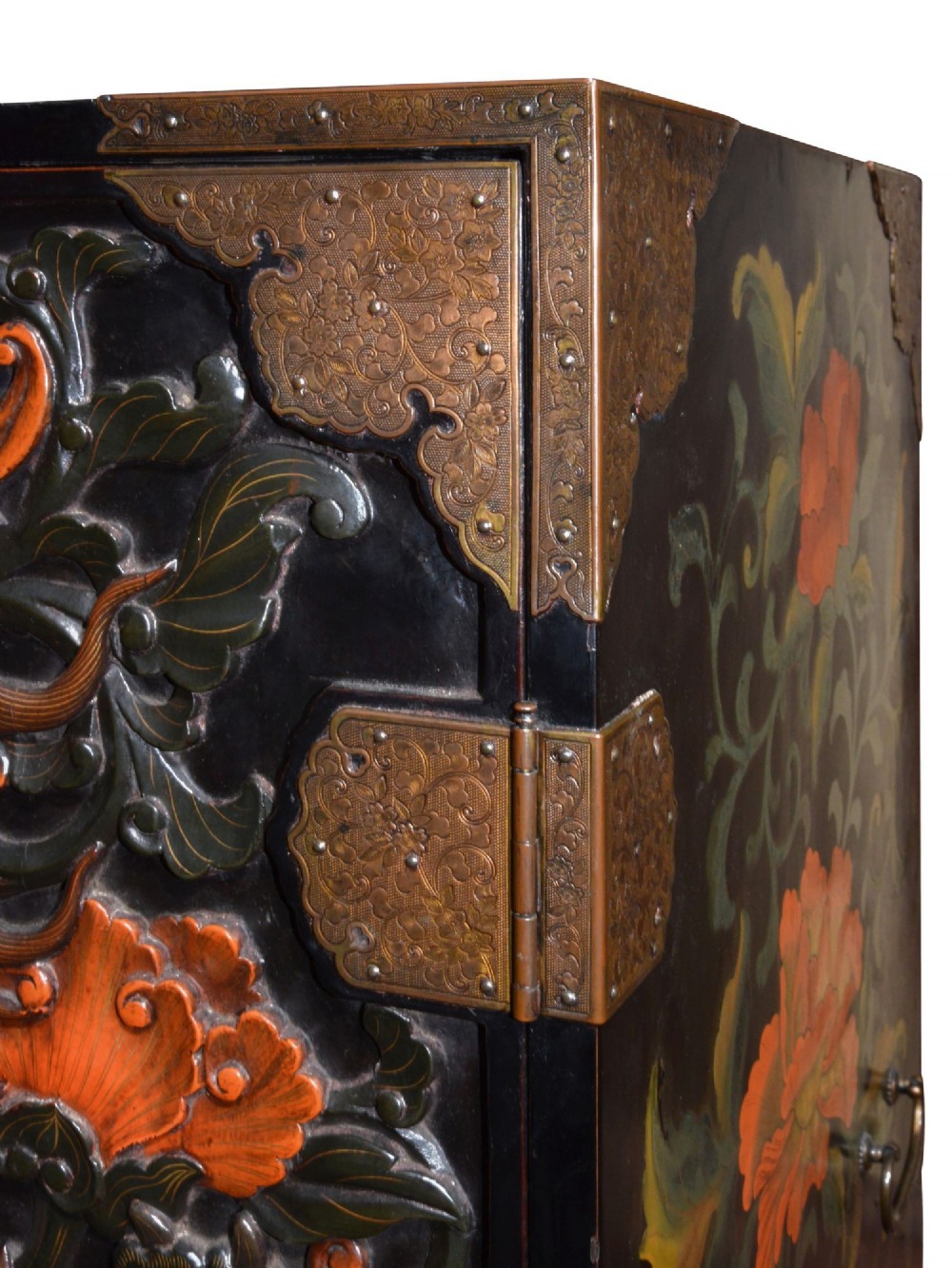 A late nineteenth-century black and polychrome carved lacquer cabinet featuring relief peony and dragon motifs, fitted brass hardware, and a matching stand base. View VI
