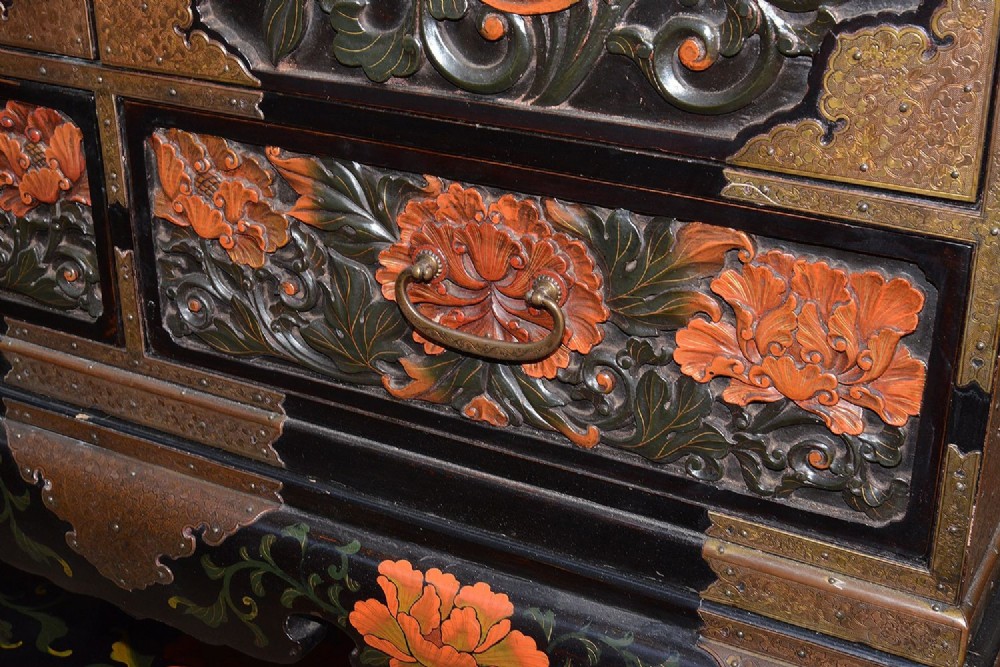 A late nineteenth-century black and polychrome carved lacquer cabinet featuring relief peony and dragon motifs, fitted brass hardware, and a matching stand base. View IX