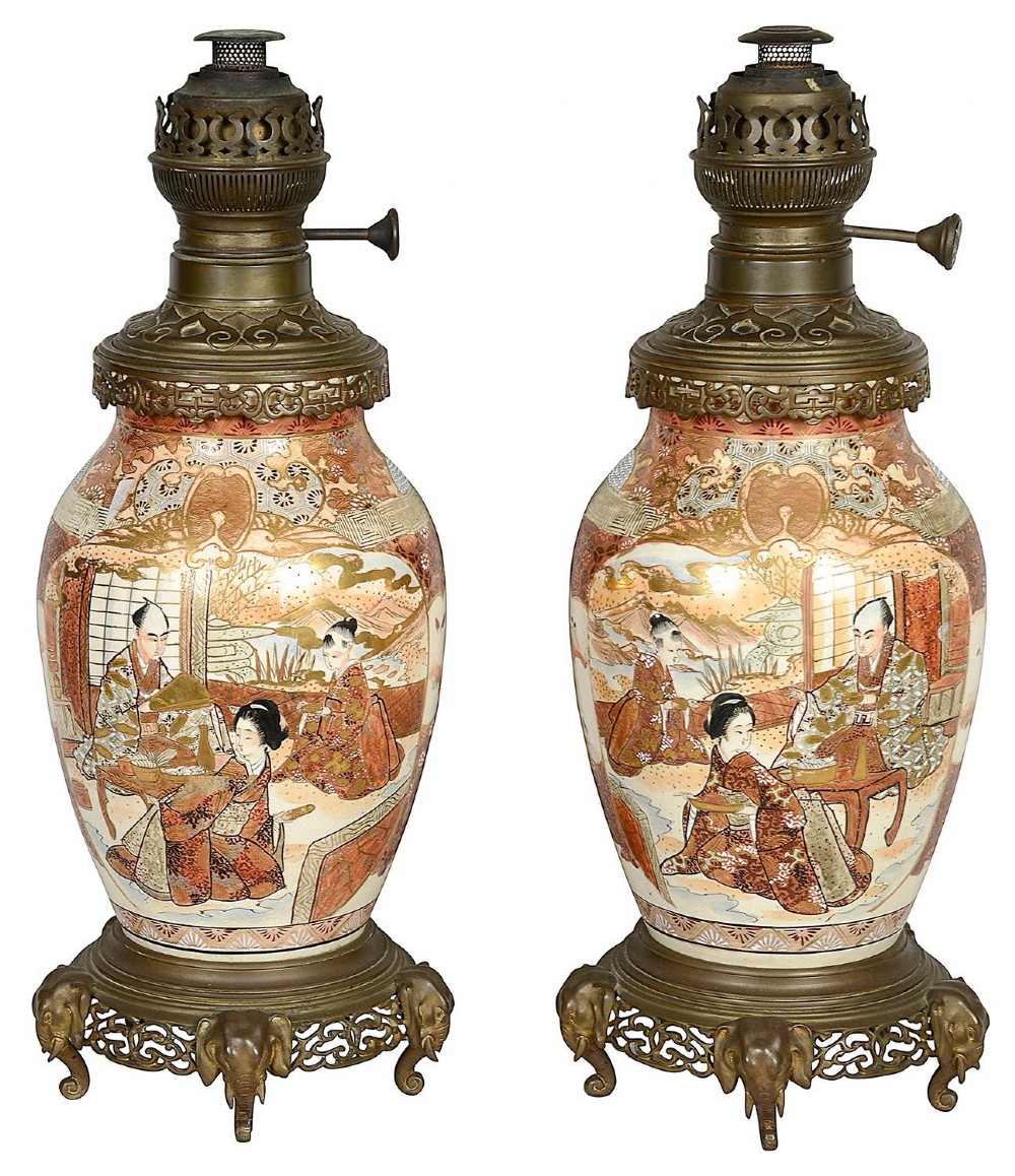 A pair of 19th-century Japanese Satsuma porcelain table lamps with brass mounts, elephant-head tripod bases, and pleated cream silk lampshades. View II