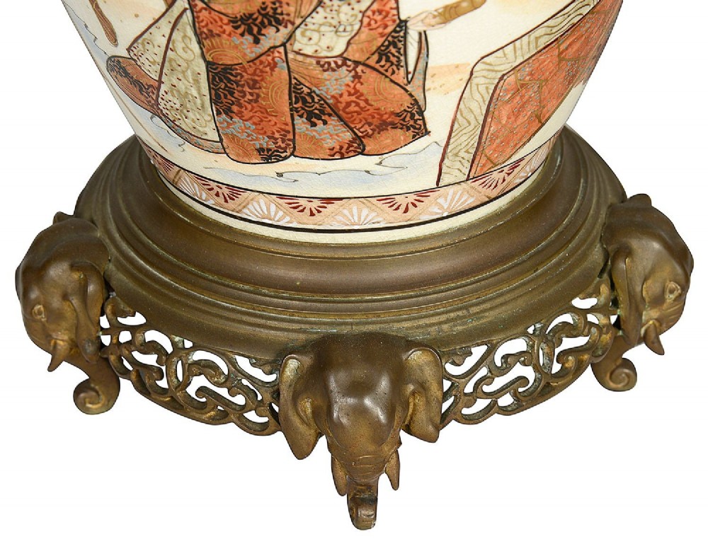 A pair of 19th-century Japanese Satsuma porcelain table lamps with brass mounts, elephant-head tripod bases, and pleated cream silk lampshades. View IX