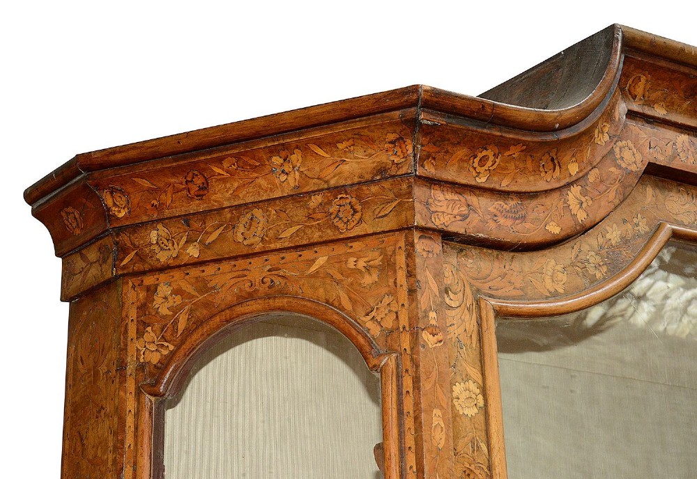 An 18th-century Dutch marquetry vitrine featuring detailed floral wood inlay, two glazed upper doors, a shaped bonnet top with carved shell cresting, a bombe three-drawer base, and claw-and-ball feet. View IV