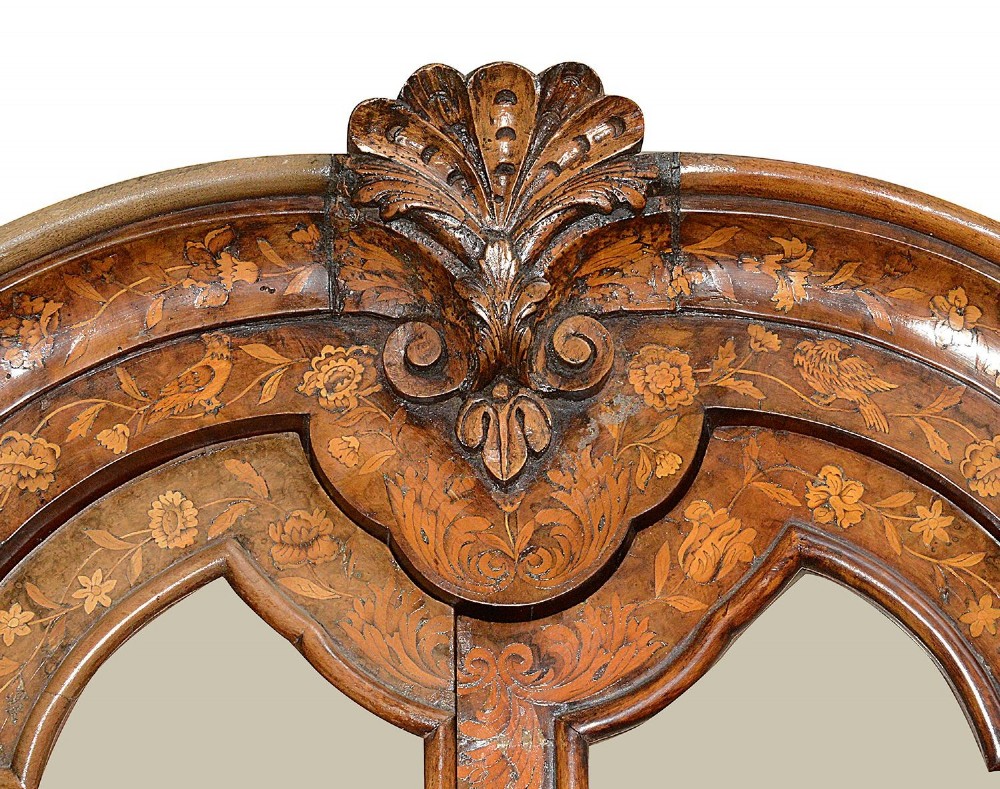 An 18th-century Dutch marquetry vitrine featuring detailed floral wood inlay, two glazed upper doors, a shaped bonnet top with carved shell cresting, a bombe three-drawer base, and claw-and-ball feet. View VI
