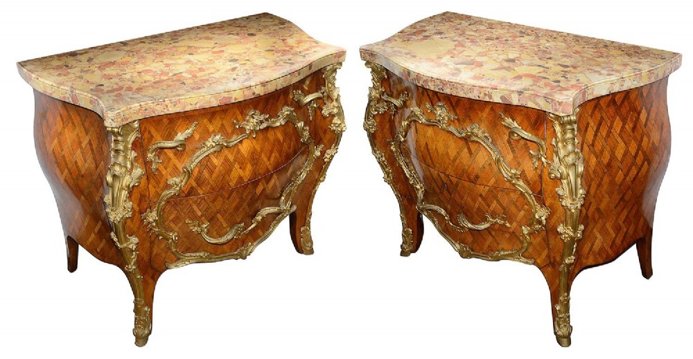A pair of French eighteenth-century style bombe commodes with geometric wood parquetry, intricate gilt-bronze mounts, and variegated marble tops.