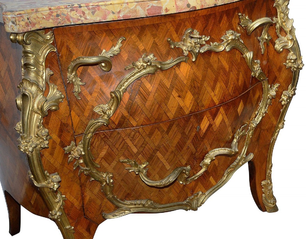 A pair of French eighteenth-century style bombe commodes with geometric wood parquetry, intricate gilt-bronze mounts, and variegated marble tops. View XII