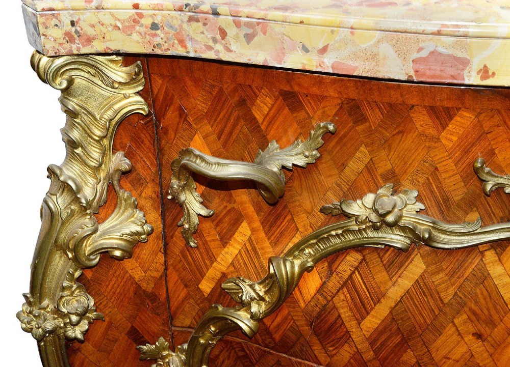 A pair of French eighteenth-century style bombe commodes with geometric wood parquetry, intricate gilt-bronze mounts, and variegated marble tops. View XIII