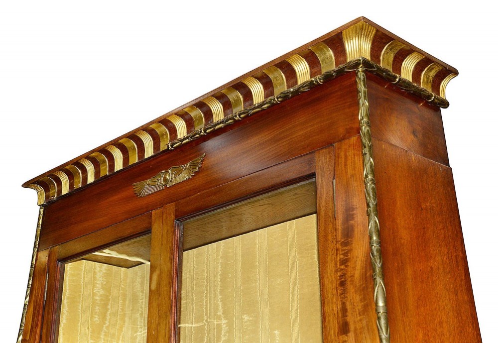A tall Art Deco mahogany display cabinet featuring ebonised Egyptian figures at the waist, glazed doors, gilt trim, and a flared top cornice. View III