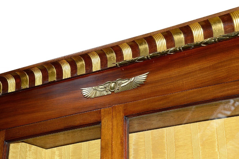 A tall Art Deco mahogany display cabinet featuring ebonised Egyptian figures at the waist, glazed doors, gilt trim, and a flared top cornice. View IV