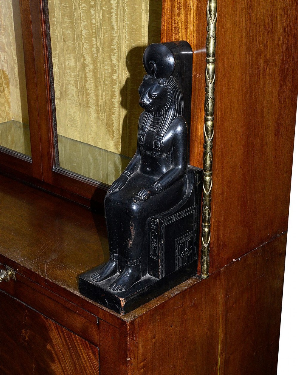 A tall Art Deco mahogany display cabinet featuring ebonised Egyptian figures at the waist, glazed doors, gilt trim, and a flared top cornice. View V