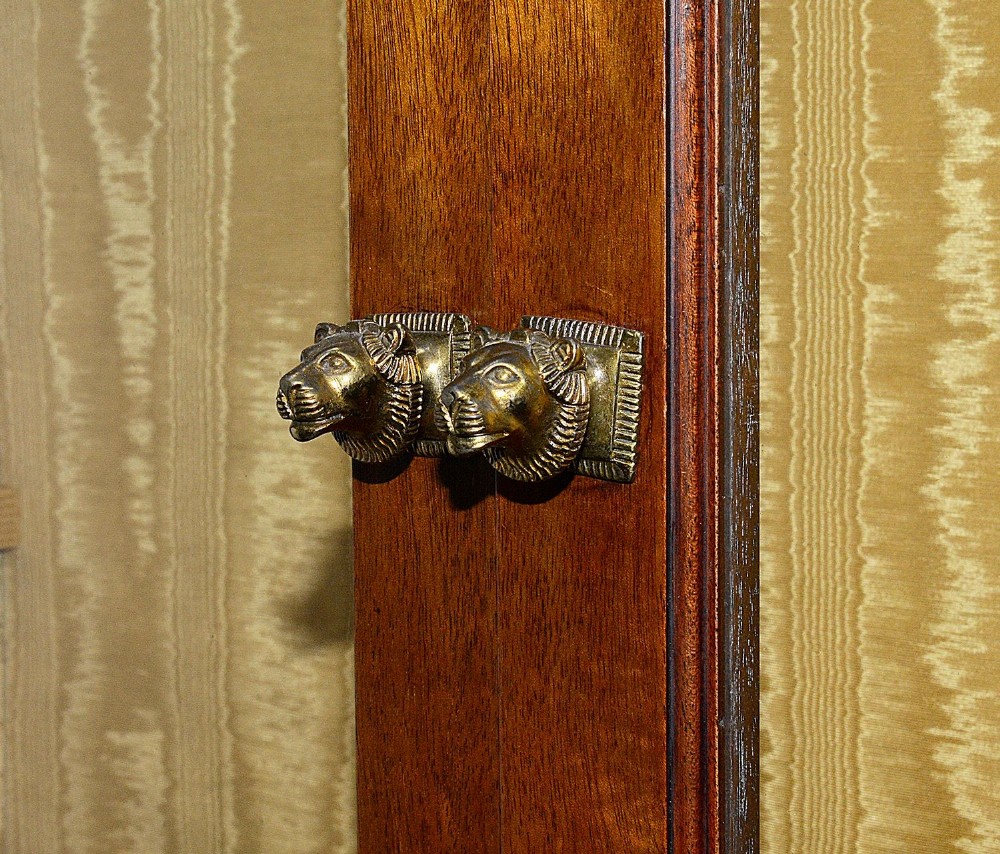 A tall Art Deco mahogany display cabinet featuring ebonised Egyptian figures at the waist, glazed doors, gilt trim, and a flared top cornice. View VI