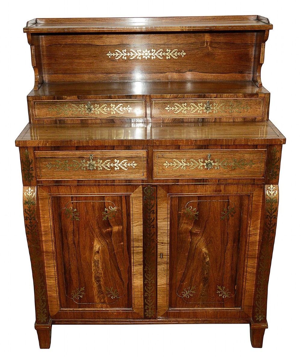 A Regency period warm brown timber chiffonier featuring intricate brass scrollwork inlay, a raised shelf gallery with two small drawers, and a two-door lower cabinet. View II