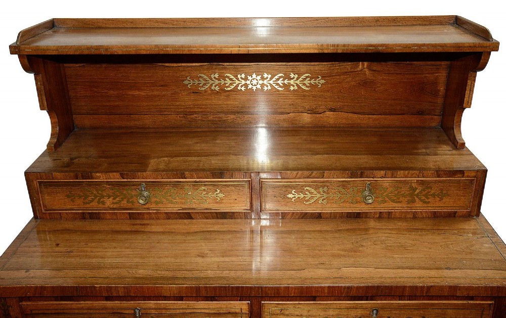 A Regency period warm brown timber chiffonier featuring intricate brass scrollwork inlay, a raised shelf gallery with two small drawers, and a two-door lower cabinet. View III