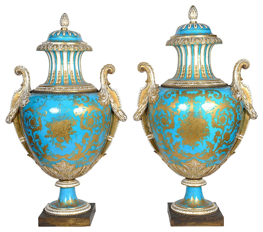A pair of turquoise blue Sevres-style porcelain urns featuring hand-painted pastoral scenes, gilded scroll handles, and pineapple finials on square metal bases. View XI