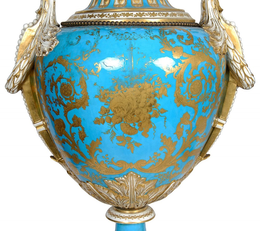 A pair of turquoise blue Sevres-style porcelain urns featuring hand-painted pastoral scenes, gilded scroll handles, and pineapple finials on square metal bases. View XII