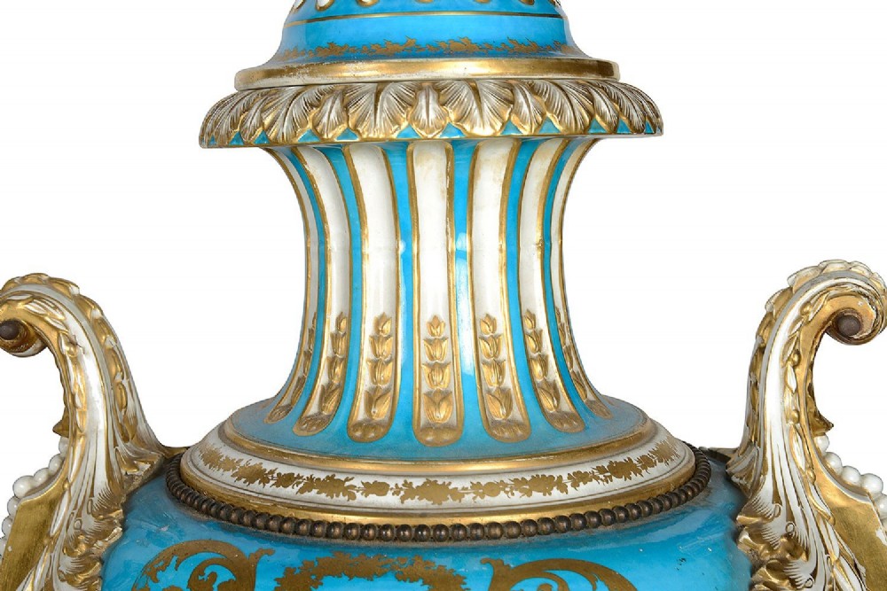 A pair of turquoise blue Sevres-style porcelain urns featuring hand-painted pastoral scenes, gilded scroll handles, and pineapple finials on square metal bases. View XIII