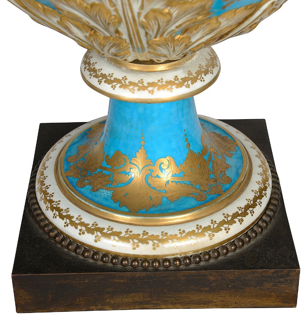 A pair of turquoise blue Sevres-style porcelain urns featuring hand-painted pastoral scenes, gilded scroll handles, and pineapple finials on square metal bases. View XIV