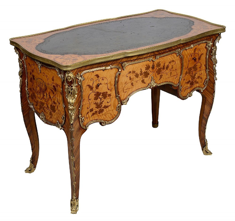 A 19th-century French Rococo Revival marquetry bureau de dame featuring floral timber inlays, serpentine edges, leather inset top, and gilt-bronze mounts on cabriole legs.