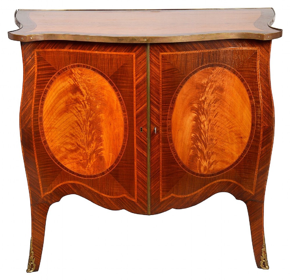 A pair of early 20th-century serpentine mahogany and satinwood commodes with oval central inlays and brass feet. View II
