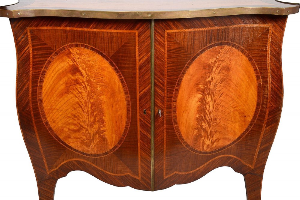 A pair of early 20th-century serpentine mahogany and satinwood commodes with oval central inlays and brass feet. View III