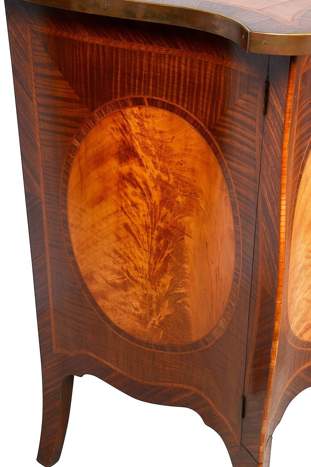 A pair of early 20th-century serpentine mahogany and satinwood commodes with oval central inlays and brass feet. View V