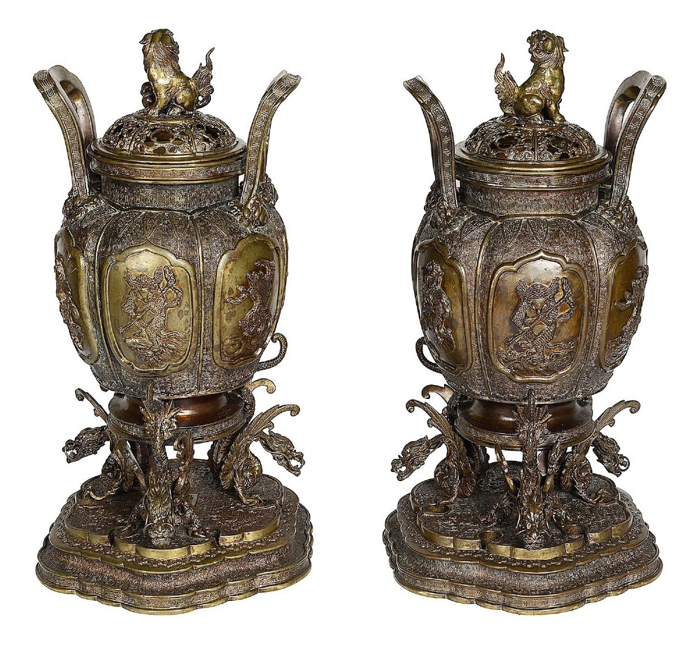 A pair of ornate antique Japanese Meiji period bronze lidded censers featuring dragon bases, relief panels, and shishi lion finials.
